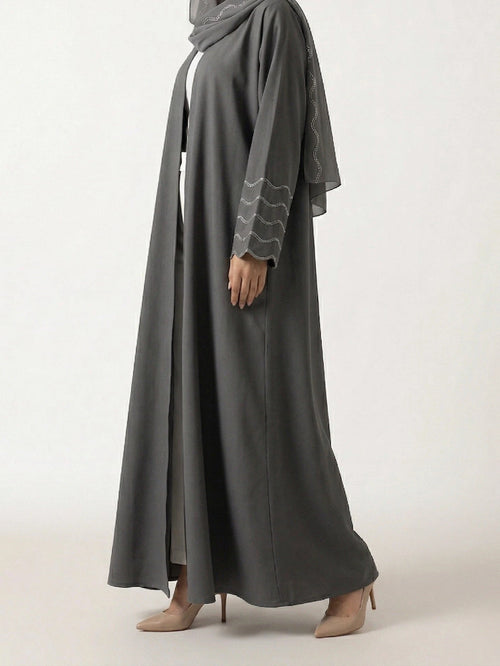 Femme portant l'Abaya Dubai Kimono Lyana gris perle en studio, vue de 3/4 sur fond neutre.